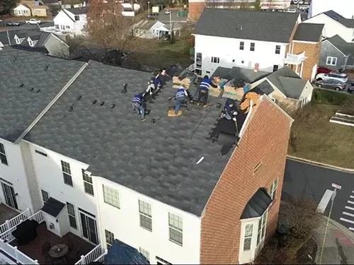 Crew installing new shingles on townhouse